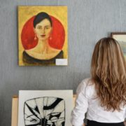 Woman Looking At Paintings Displayed On The Wall